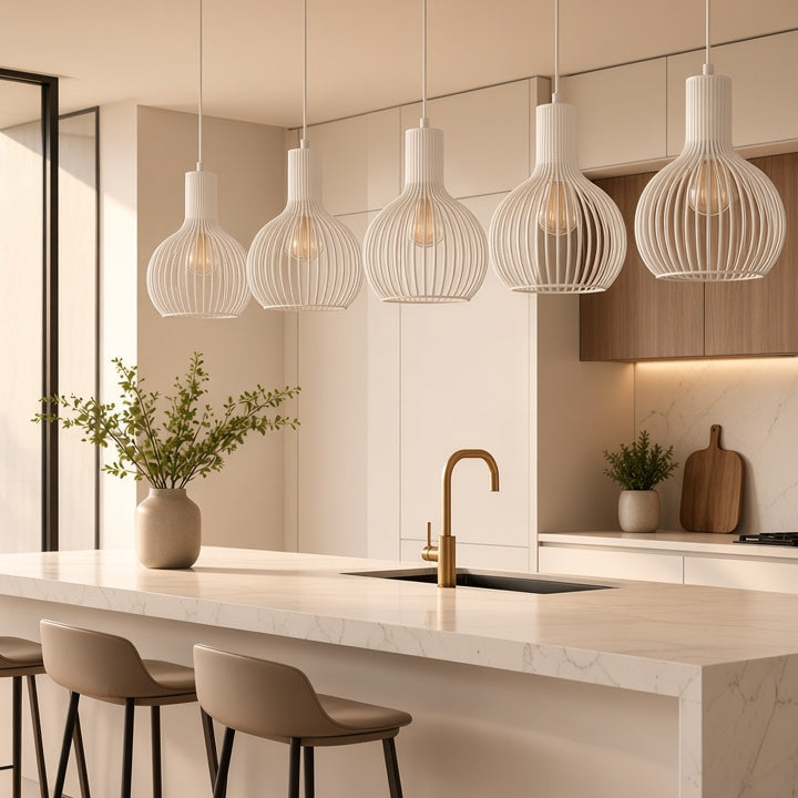 A modern kitchen interior with a large white marble island, three upholstered bar stools, pendant lights, wood cabinetry, and a gold faucet. No person or animal is present, but this is still a real environment rather than a clean isolated product shot, so subject_type is Lifestyle.
